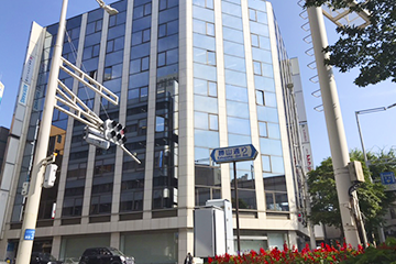 道の左手に「福岡ひびき信用金庫」がある十字路の横断歩道を渡った目の前のビルが「北九州東洋ビル」です。